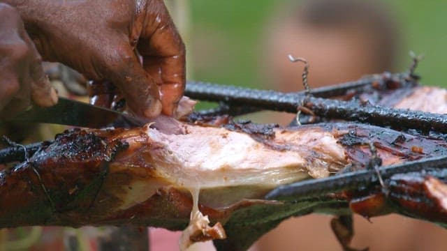 Grilled whole pig barbecue being sliced outdoors
