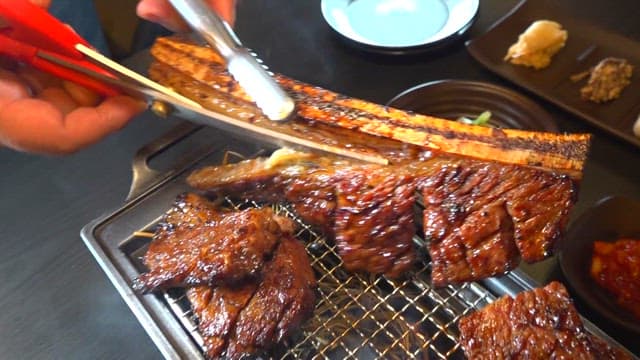 Cutting marinated ribs while they are grilled