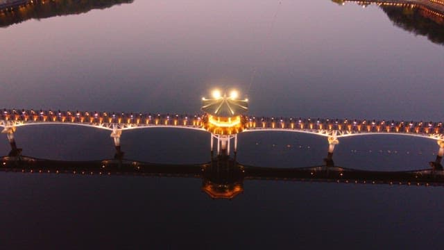 Illuminated bridge over calm river at night