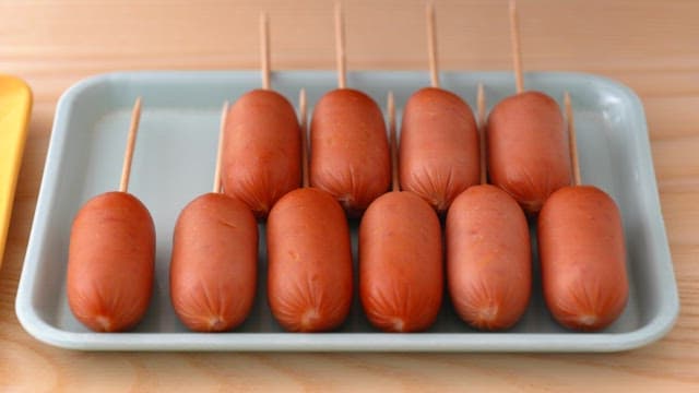 Sausages on skewers arranged on a tray