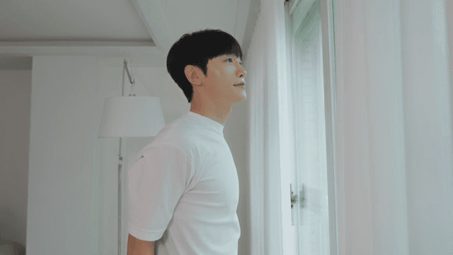 Man Stretching by the Window in a Bright Living Room