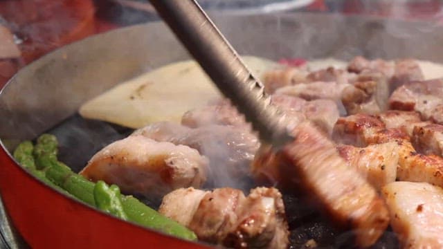 Grilling vegetables and pork belly on a restaurant grill