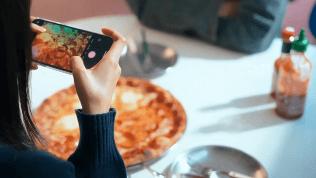 Woman taking photos of a pizza indoors
