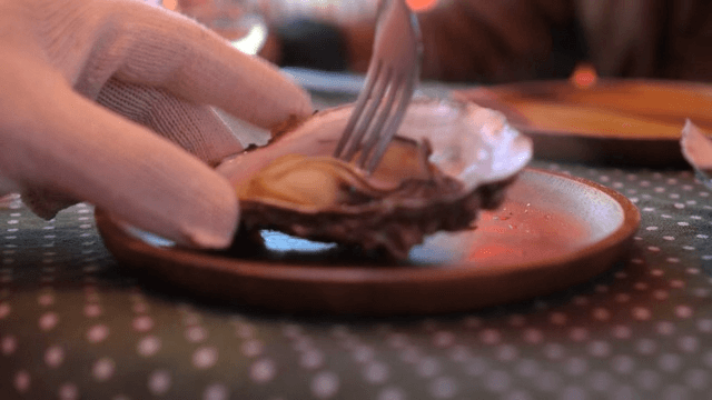 People wearing gloves eating oysters on a cozy table
