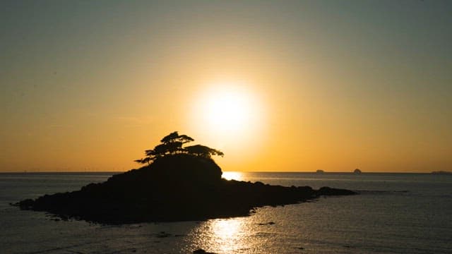 Sunset Disappearing Below the Horizon Beyond a Small Island