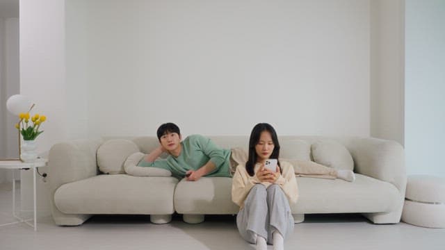 Using a smartphone and a man watching television on a sofa