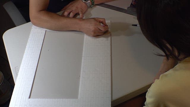 Two people working together on a crafting project with paper indoors