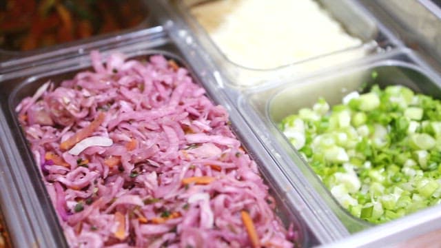 Salad and kimchi in stainless steel bowl on food preparation table