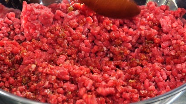 Mixing minced beef and seasoning in a metal bowl
