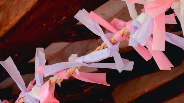 Person tying a piece of paper with a wish written on it to the rope of a traditional house