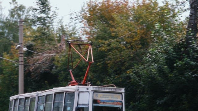 Red tram moving through the town streets near a building
