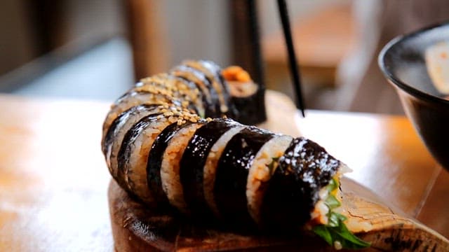 Kimbap being picked up with chopsticks