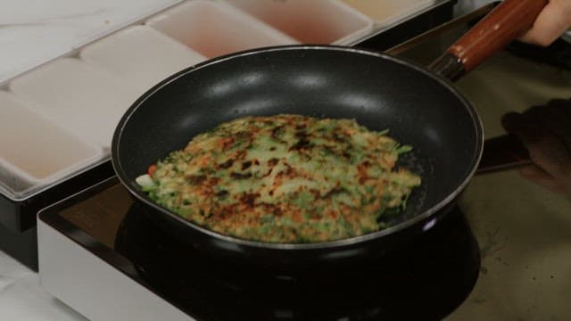 Water parsley pancake cooked with a flipper in an oiled frying pan