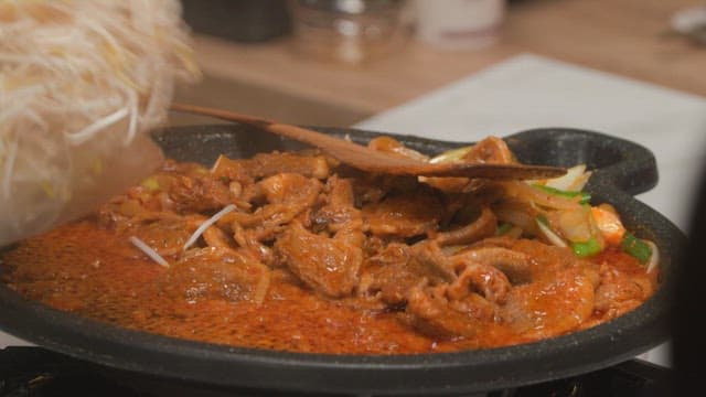 Cooking stir-fried spicy pork with bean sprouts in a kitchen
