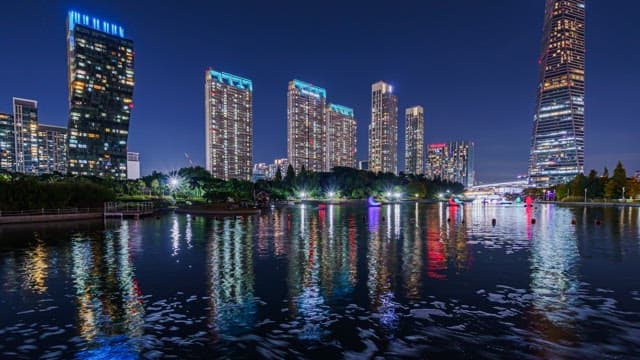 Illuminated Cityscape Reflecting on Lake of Park at Night