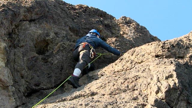 Climber Ascending a Rocky Cliff