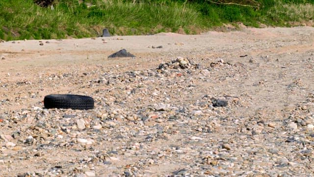 Gravel field with green space and tires