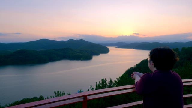 Person enjoying a sunset view over a lake