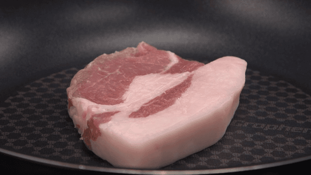Raw pork slices being placed in a pan