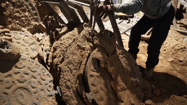 Worker handling manhole covers in a factory