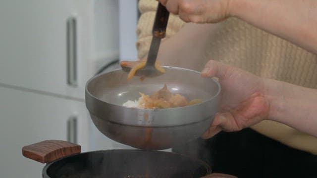 Ladle is used to ladle freshly made stew into a metal bowl in the kitchen