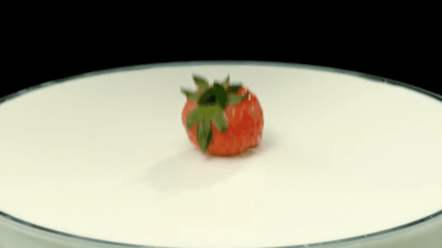 Red strawberries falling into white milk