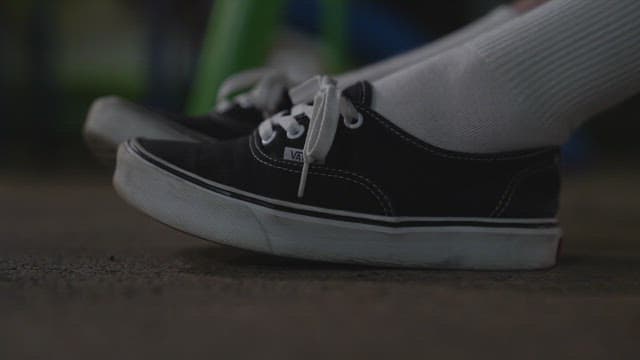 Person wearing black sneakers with white laces