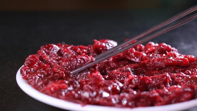 Delicious sliced raw bottom round steak dipped in seasoning sauce