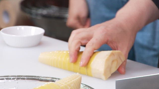 Cutting boiled bamboo shoots with a knife on a cutting board