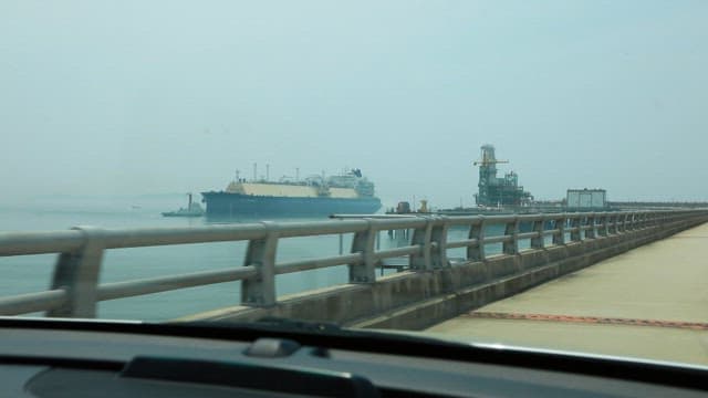 Large cargo ship near an industrial docking station on a cloudy day
