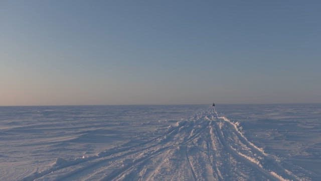 Vehicle Traversing Snowy Terrain Under Clear Sky