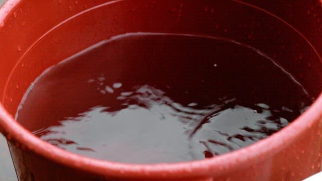 Raindrops falling into a red bucket of water
