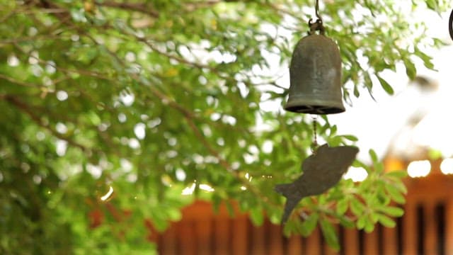 Tranquil outdoor scene featuring a hanging bell with a fish design