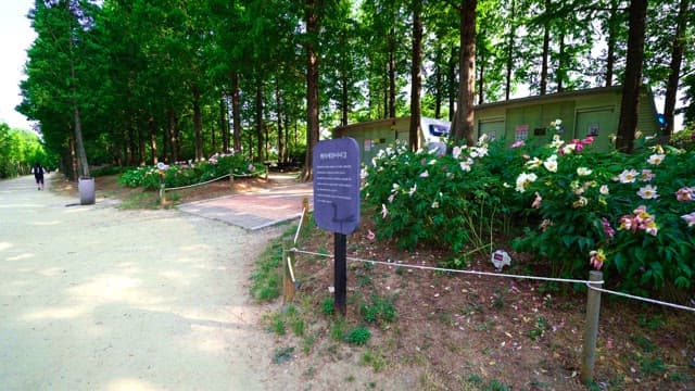 Information board in a park with a flower garden and green trees