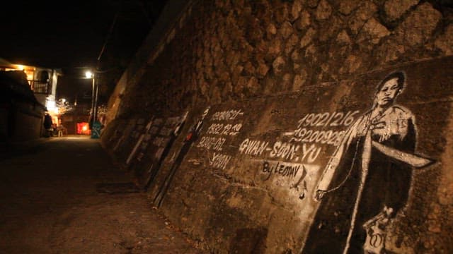 Passerby passes by graffiti depicting great Korean figures