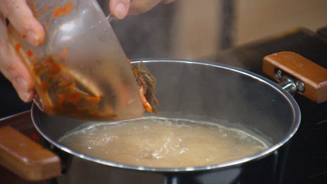 Green onion kimchi added to the soup boiling in a pot
