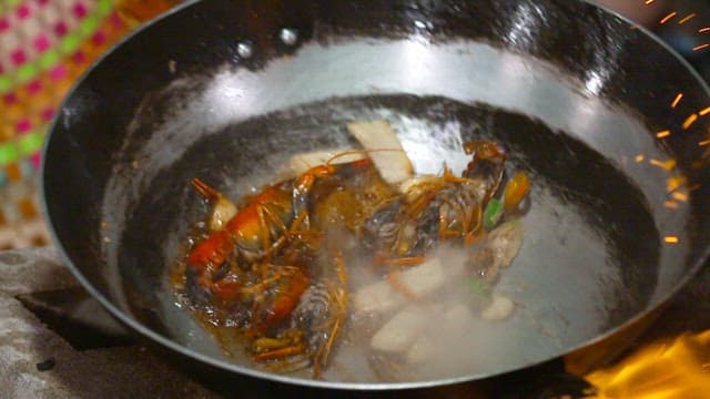 Lobsters being cooked in a pan with flames