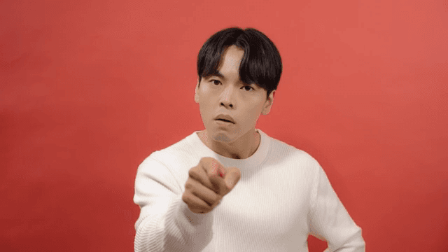 Angry man wearing white sweater pointing to front with finger