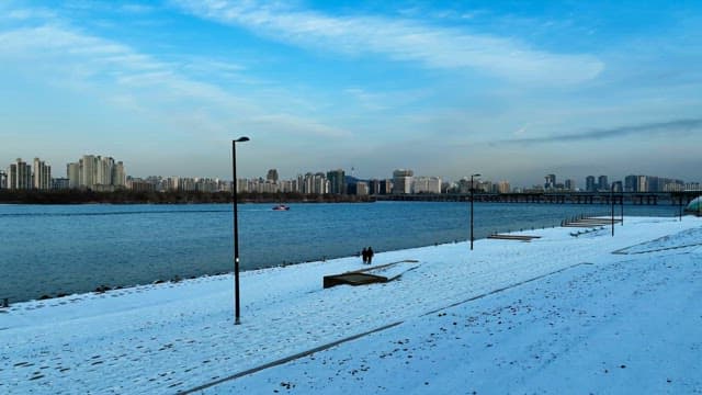 Snow-Covered Riverside City Under Blue Sky