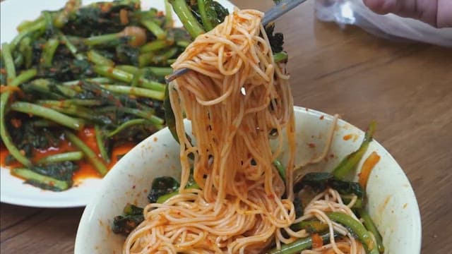 Fresh pickled radish kimchi and pickled radish noodles eaten with chopsticks