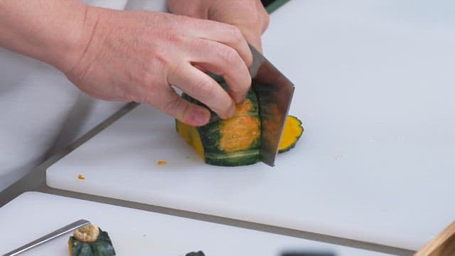 Cutting Pumpkin with a Knife on a Cutting Board in the Kitchen