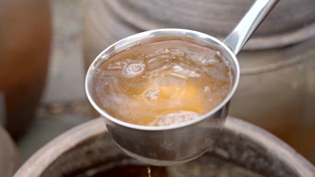 Pouring soy sauce into a crock using a ladle