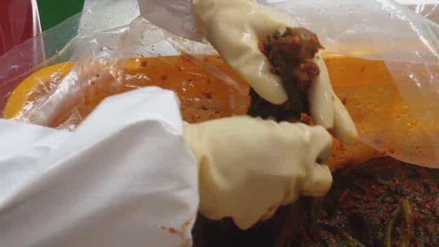 Person preparing and packaging traditional kimchi