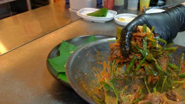 Seasoned meat plated with perilla leaves in the kitchen