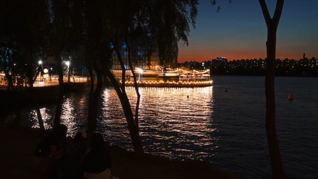 Brightly lit buildings floating on water and a sunset city skyline
