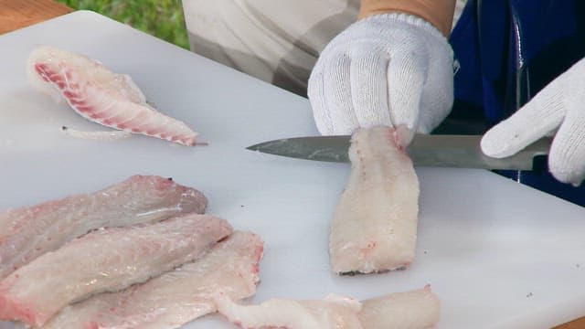 Peeling fresh fish fillets on a cutting board