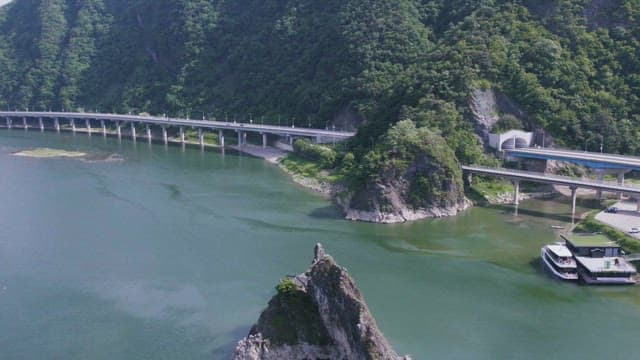 Aerial View of a Bridge Between Scenic River and Mountain