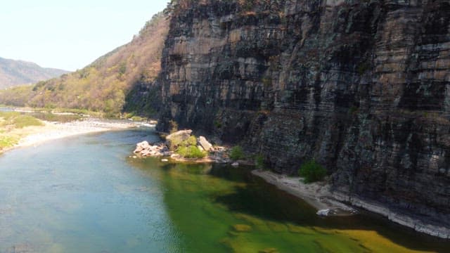 Tranquil river flowing beside a cliff