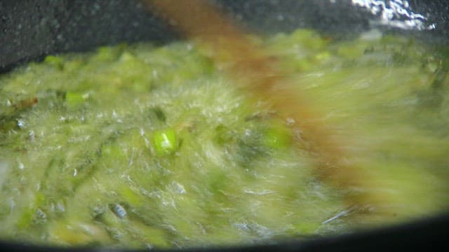 Green onions being stirred in a pan