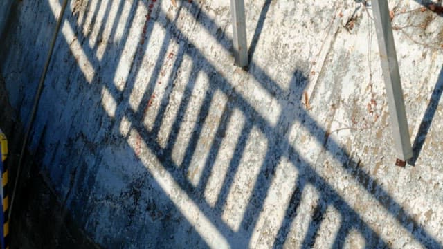Shadows of a railing cast on a weathered wall